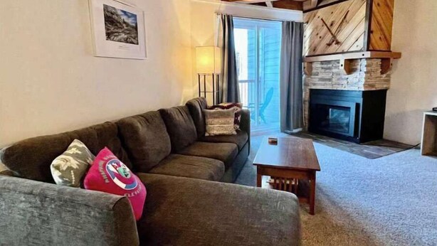 A living room with a sofa, a small table, a fireplace, and a window with curtains. - 2 BR Mountain Condo w/ views, near amazing skiing (Silverthorne)