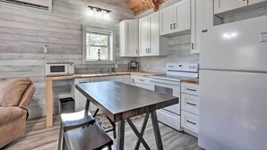 Cocina compacta con armarios blancos, microondas, estufa y refrigerador.