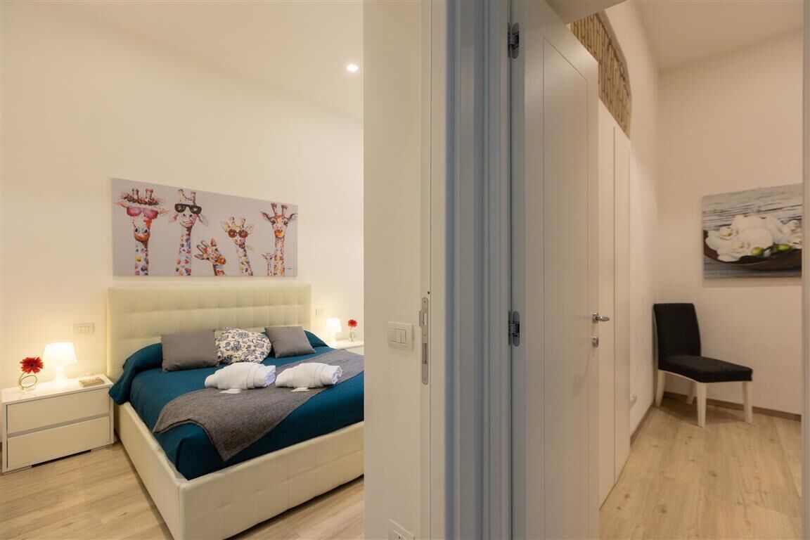 A bedroom with a bed, nightstands, a chair, and artwork on the walls.