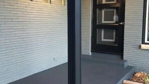 A modern building with a dark grey exterior, a brick wall, and a black-framed door. - {{{ Mid-Century Modern }}} Newly renovated 3 BR (Two Rivers)