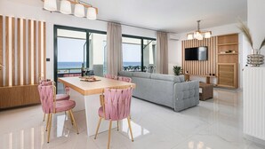 Ein modernes Wohnzimmer mit Essbereich, einem grauen Sofa und einem an der Wand befestigten Fernseher.