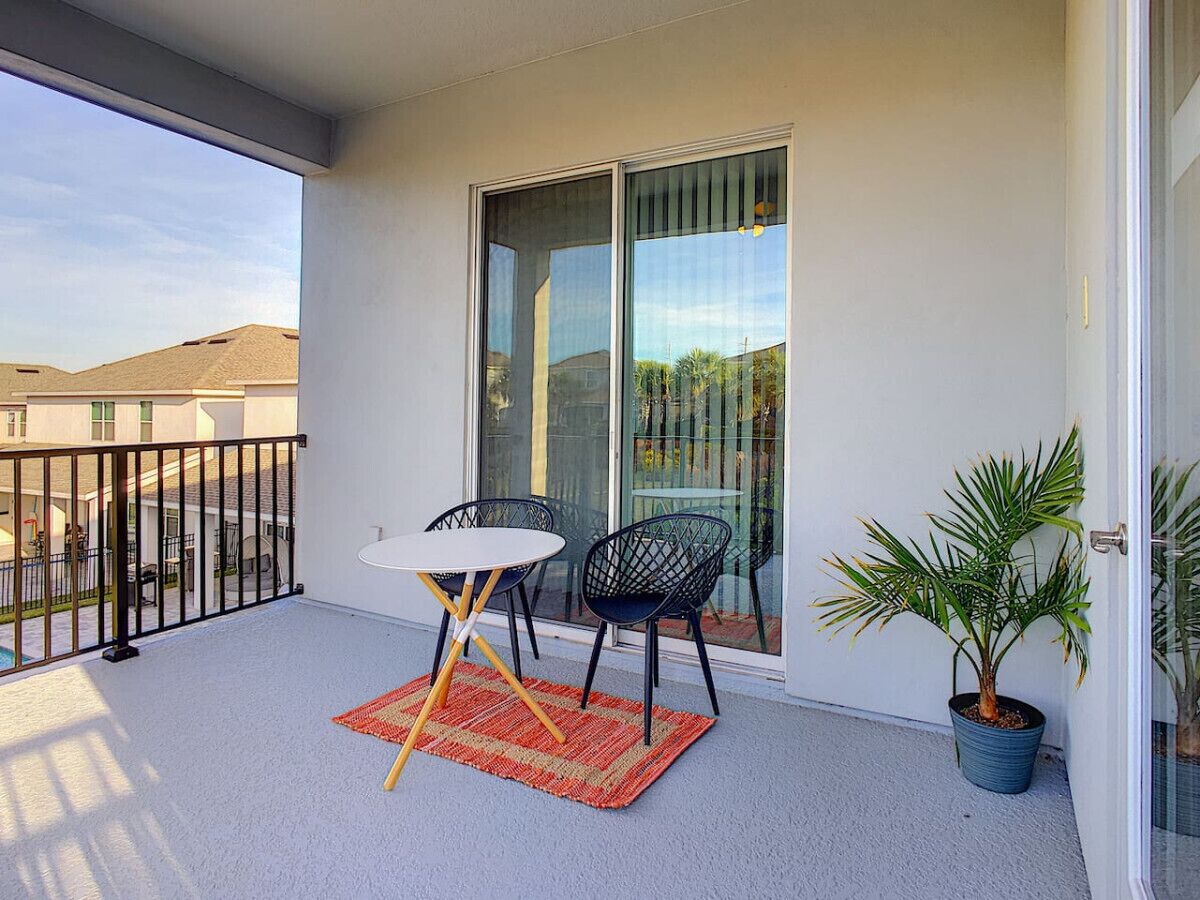 Ein Balkon mit Tisch und Stühlen, einem Blumentopf und einer Schiebetür.