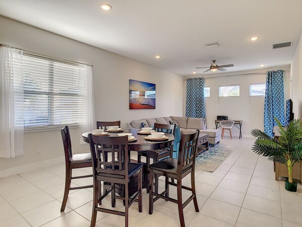 A spacious living area with a dining table, sofa, and a ceiling fan. - Elite Resort -Vacation home- 3BDRM w/ pool (Kissimmee)