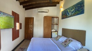 Un dormitorio con cama, armario, estante, un cuadro y un equipo de aire acondicionado.