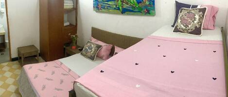 Un dormitorio con cama, armario, cuadro y una mesita.