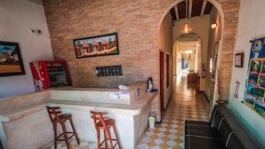 Un área de bar con piso a cuadros, una barra con taburetes y un mural en la pared.