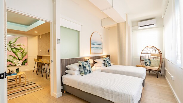 A modern hotel room with two beds, a dining area, and a view of the ocean. - Charming 4-Bedroom Retreat in Heart of Condado (San Juan)