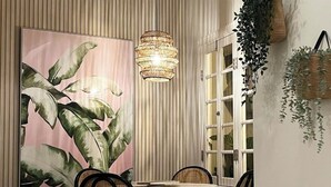 A dining area with a white table and four chairs, a large tropical plant painting, a woven pendant light, and a patterned floor. - Charming 4-Bedroom Retreat in Heart of Condado (San Juan)