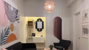A modern living room with a black sofa, a wooden coffee table, a black chair, and a decorative wall piece. - Charming 4-Bedroom Retreat in Heart of Condado (San Juan)