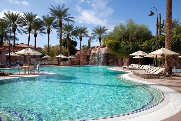 Relax by the pool surrounded by palm trees and a soothing waterfall.