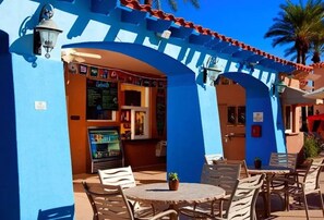 Relax in a tranquil outdoor seating area with tables and chairs under a covered structure.