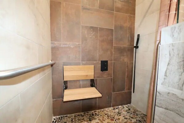Un espace douche doté d’un banc, de murs carrelés et d’un mur d’accent en marbre.