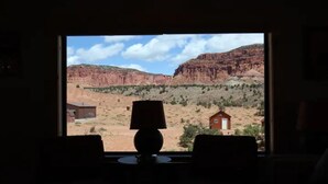 Una habitación con un amplio ventanal que da a un paisaje desértico con formaciones rocosas rojas y vegetación escasa.