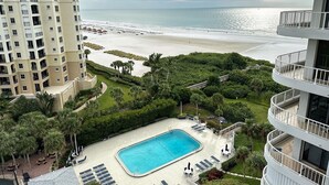 A hotel with a swimming pool, beach view, and lush greenery. - Beachfront Condo available on a Monthly Basis Only (Marco Island)