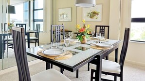 A dining area with a glass table, chairs, and a vase of flowers. - Beachfront Condo available on a Monthly Basis Only (Marco Island)