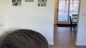 Una habitación con un gran sillón de peluche, una mesa de comedor con sillas y obras de arte en las paredes.
