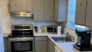 Una cocina funcional con electrodomésticos de acero inoxidable, gabinetes grises y lavavajillas.