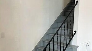 Una escalera con barandilla de metal negro y peldaños de gris claro.