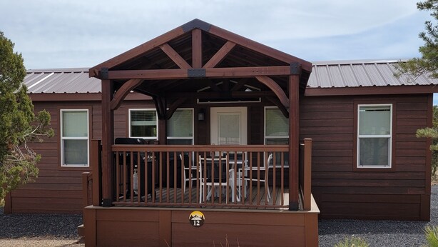 Eine Holzhütte mit Veranda, einem Schild mit der Nummer 12 und einer Schotterauffahrt.