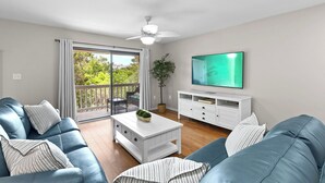 Una sala de estar moderna con un sofá azul, una mesa de centro blanca y un televisor en la pared.
