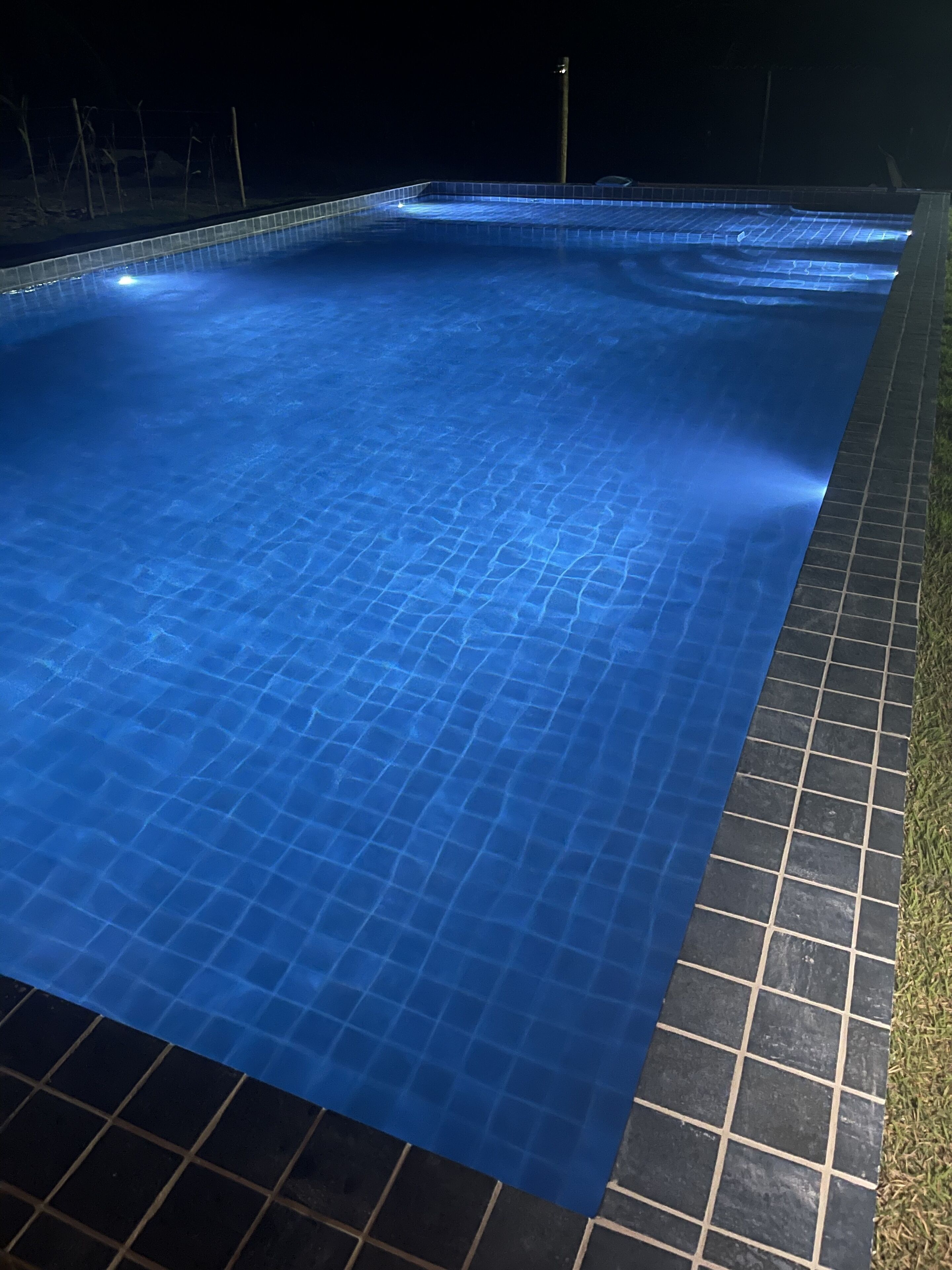 Una piscina con borde de azulejos y contorno oscuro.