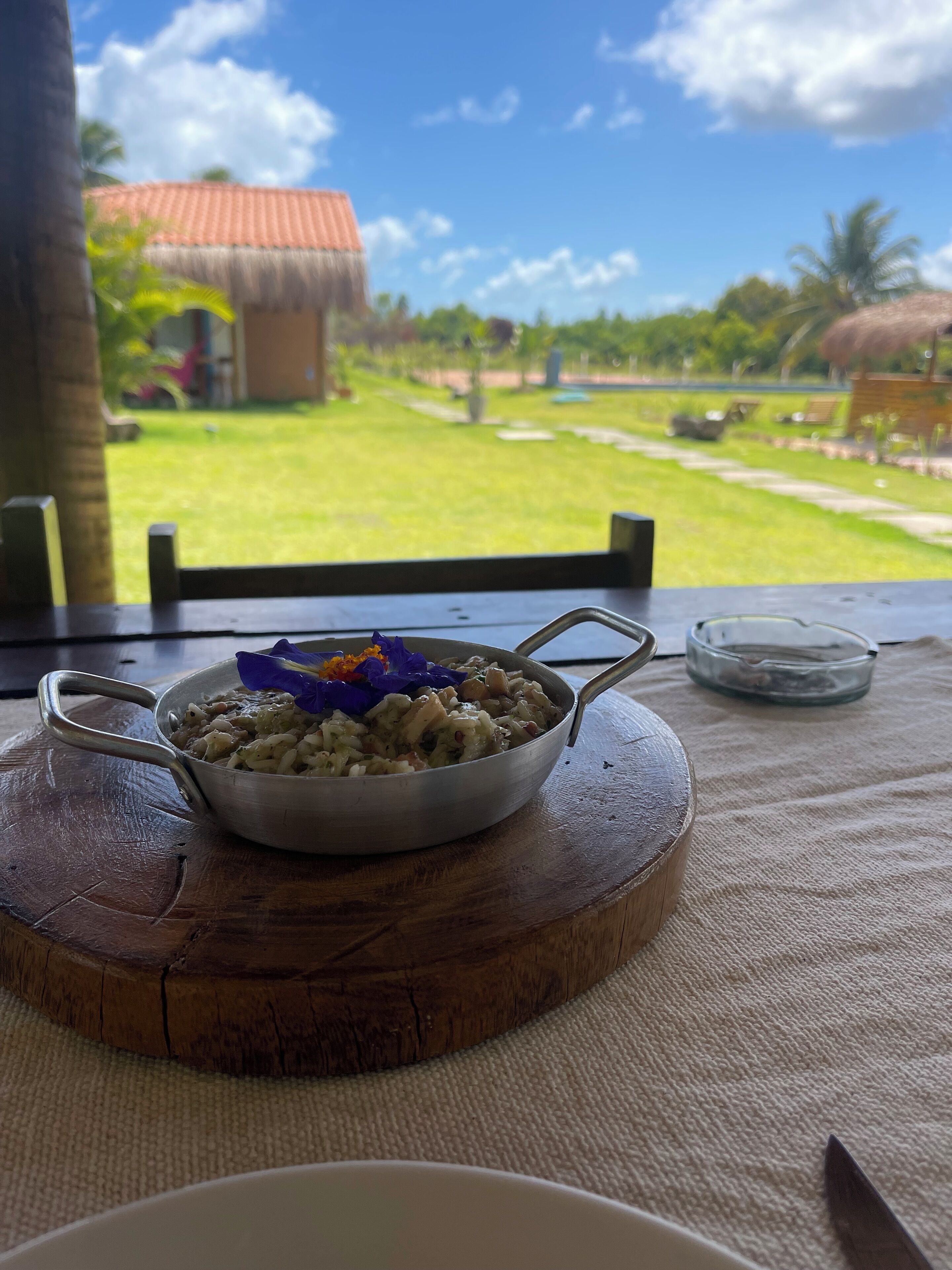 Un plat sobre una taula de fusta amb vista a una casa de teules i un jardí.