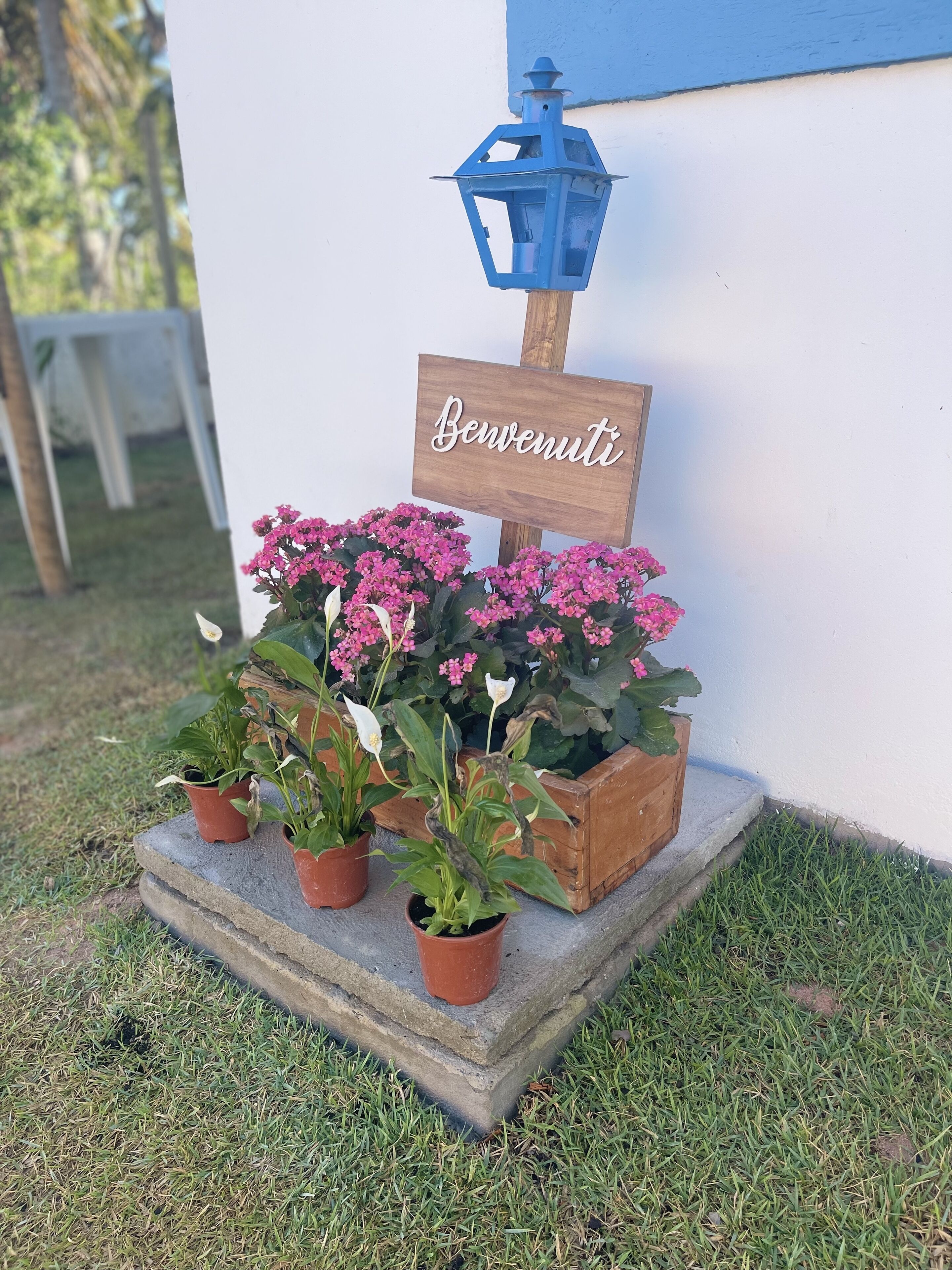 A welcome sign with potted plants and a lantern.