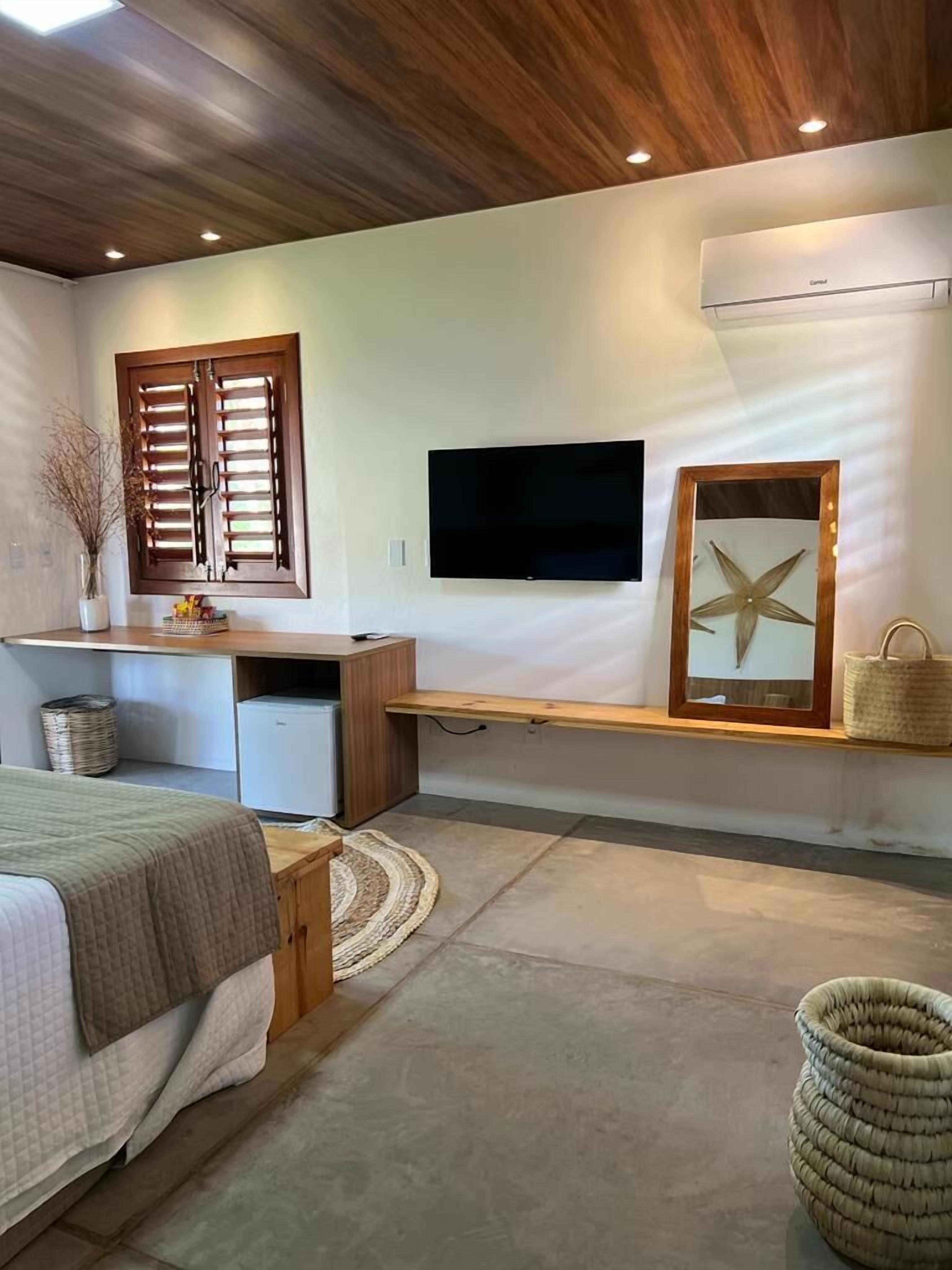 Une chambre à coucher avec un lit, un bureau, une télévision, une décoration en forme d’étoile de mer et un panier en osier.