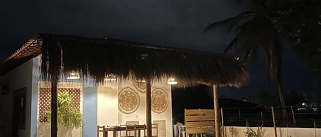 A thatched-roof building with a dining area and a small garden.