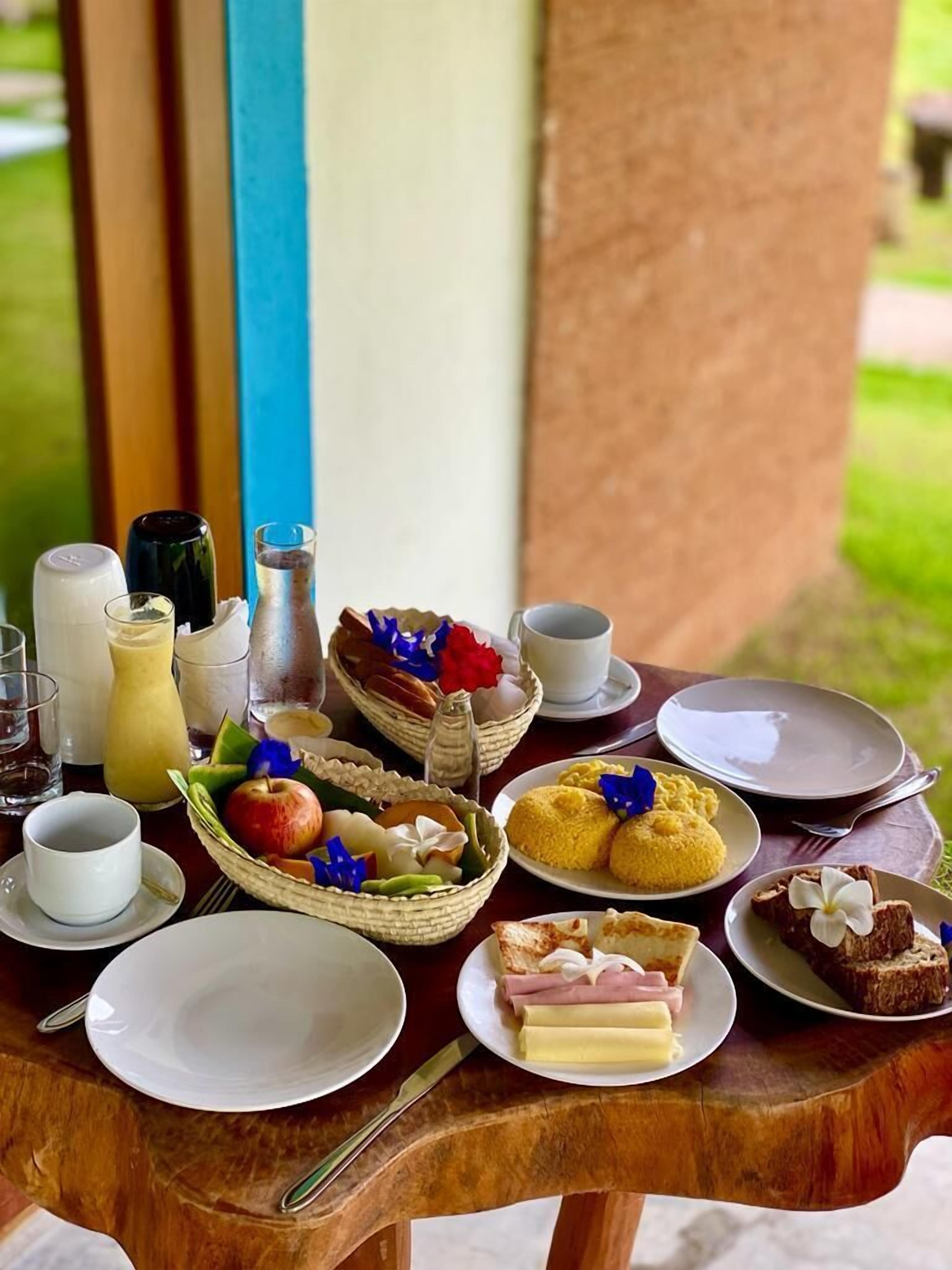 A table set with various breakfast items including fruits, pastries, and beverages.