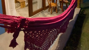 A room with a bed, a table with chairs, and a hammock. - Pousada Corália (São Miguel dos Milagres)