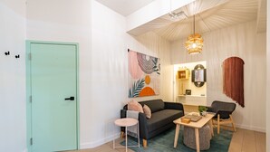 A modern living room with a teal door, a grey sofa, a small round table, and a coffee table. - Condado Beach Chic - Walk everywhere (San Juan)