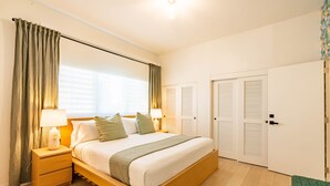 A bedroom with a wooden bed, a nightstand, a lamp, and a window with curtains. - Condado Beach Chic - Walk everywhere (San Juan)