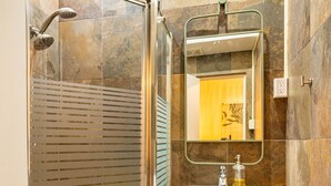 A modern bathroom with a glass-enclosed shower, a vanity with a sink, and a mirror above it. - Condado Beach Chic - Walk everywhere (San Juan)