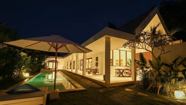 A modern house with a swimming pool, outdoor seating, and a well-lit patio area. - 2 bedrooms Luxury Villa in Ubud with private pool (Gianyar Regency)