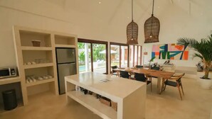 A modern kitchen with a central island, open shelving, and a dining area with a table and chairs. - 2 bedrooms Luxury Villa in Ubud with private pool (Gianyar Regency)