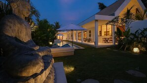 A modern house with a large patio, outdoor seating, and a stone sculpture. - 2 bedrooms Luxury Villa in Ubud with private pool (Gianyar Regency)