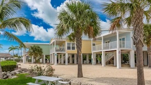 Ein Strandhotel mit mehreren Balkonen, Palmen und einem Picknicktisch.
