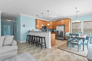 A modern kitchen with wooden cabinets, a central island with stools, and pendant lighting.