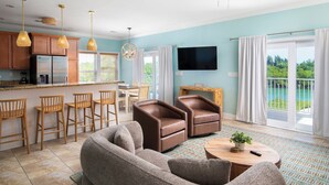 Ein modernes Wohnzimmer mit einer Couch, Sesseln, einem Couchtisch und einem Fernseher.