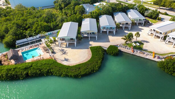 Eine Luftaufnahme eines Resorts mit mehreren Gebäuden, einem Swimmingpool und einer begrünten Anlage mit einem Wasserspiel.