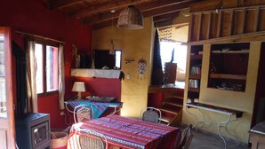 Um quarto acolhedor com uma mesa de madeira, cadeiras, um fogão e uma estante de livros.