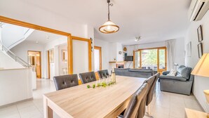 A spacious living area with a wooden dining table, grey sofas, and a staircase leading to another room. - House with pool Sirenas Playa de Muro (Playa de Muro)