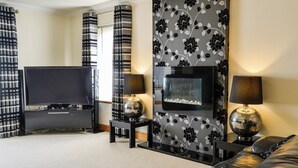 A modern living room with a flat-screen TV, a fireplace, and two lamps. - Conveniently located just 500 yards from the sandy beach. (Southerness, near Dumfries)
