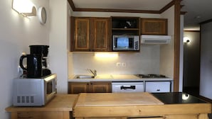 Une cuisine compacte dotée de meubles en bois, d’un four à micro-ondes, d’une machine à café et d’un évier.