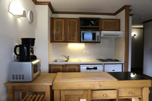 A compact kitchen with wooden cabinets, a microwave, a coffee maker, and a sink. - 2nd floor, view open, balcony, tv, ski locker, 50m², Aussois (Aussois)