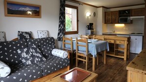 Un salon confortable avec un canapé et une table à manger, une cuisine équipée des appareils de base et une fenêtre avec des rideaux.