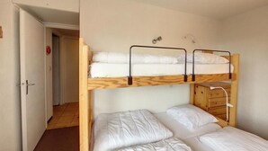 Een slaapkamer met stapelbed en een deur naar een andere kamer.
