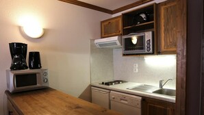 Una cocina compacta equipada con microondas, cafetera y un refrigerador pequeño.
