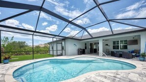 Une piscine dotée d’une enceinte en verre, un espace patio avec des meubles d’extérieur et une vue sur le paysage environnant.